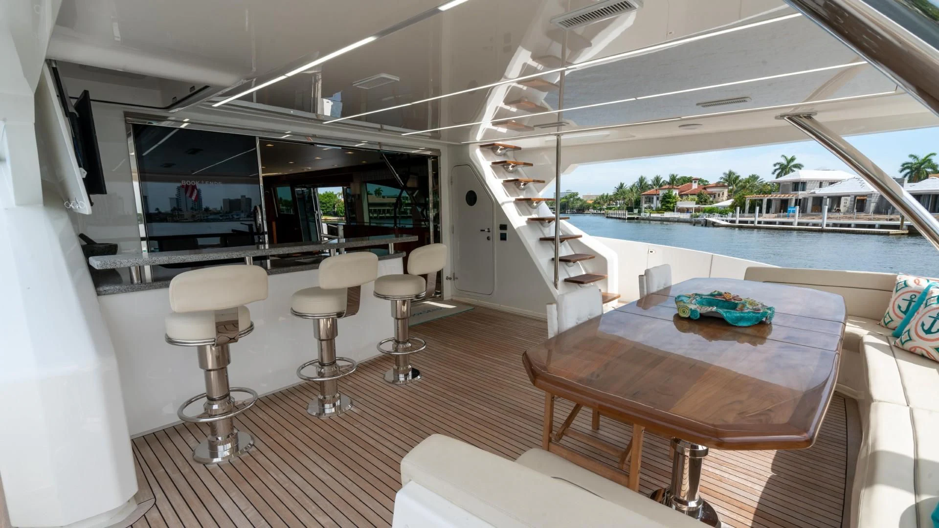 a room with a table and stools and a staircase aboard OBSESSION Yacht for Sale