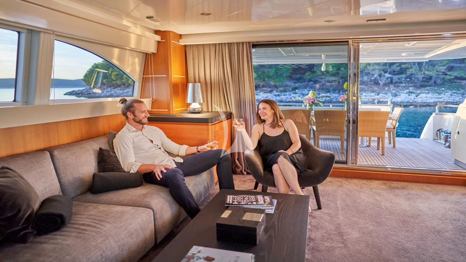 a man and a woman sitting on a couch in a room with a table and chairs aboard KARISMA Yacht for Sale