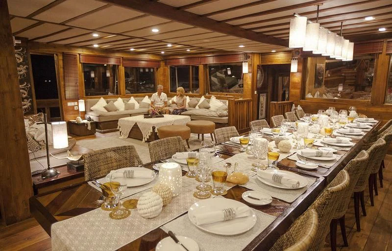 a group of people sitting at a table with plates and glasses aboard PRANA Yacht for Charter