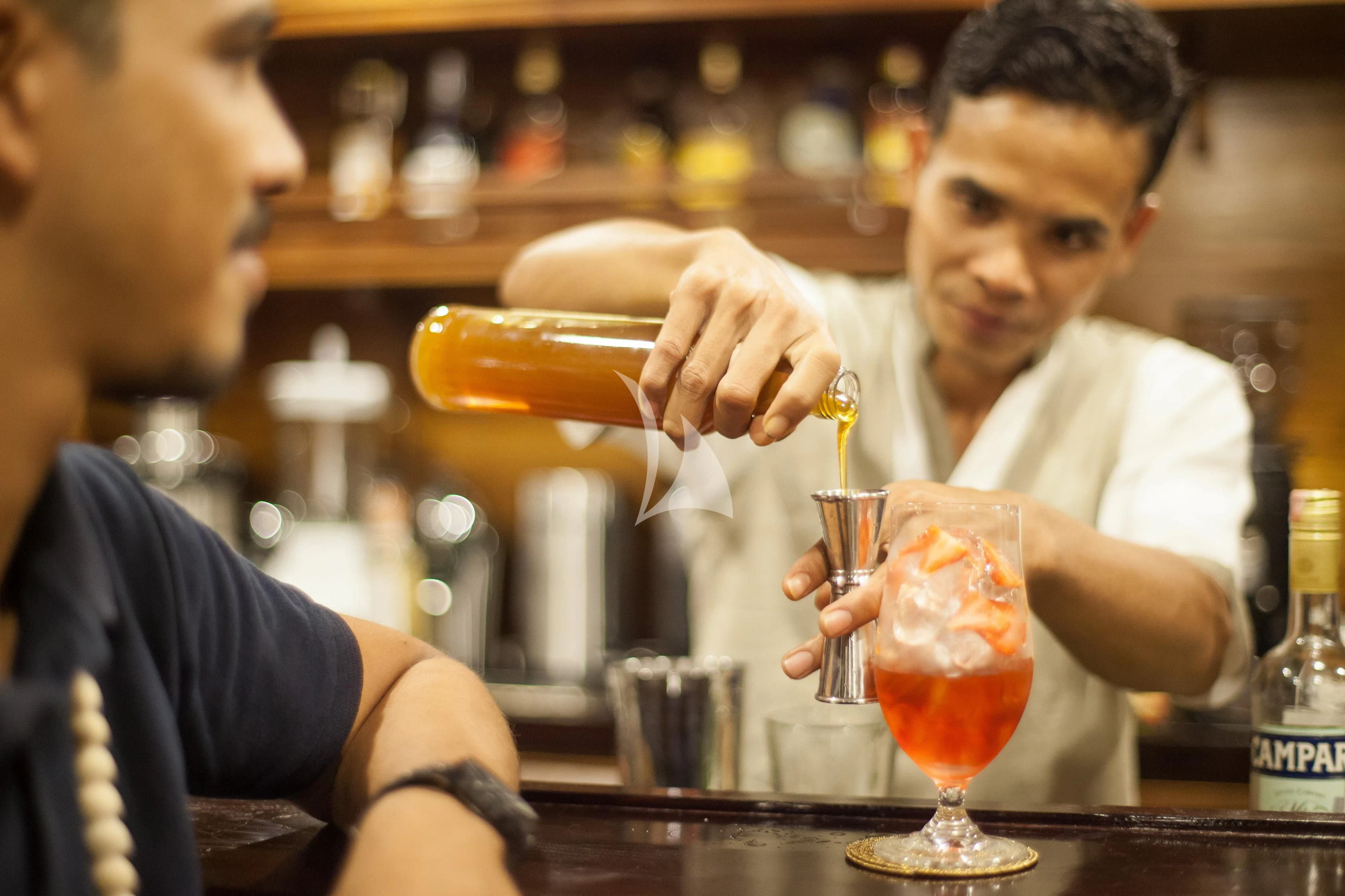 a person pouring a drink into a glass aboard PRANA Yacht for Charter
