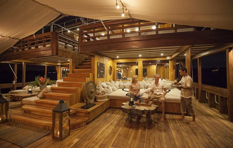 a group of people sitting on a couch in a large room aboard PRANA Yacht for Charter