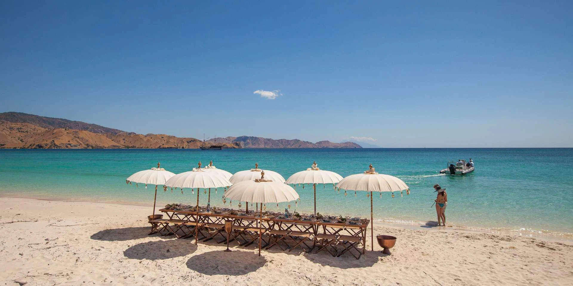 a beach with umbrellas and chairs aboard PRANA Yacht for Charter