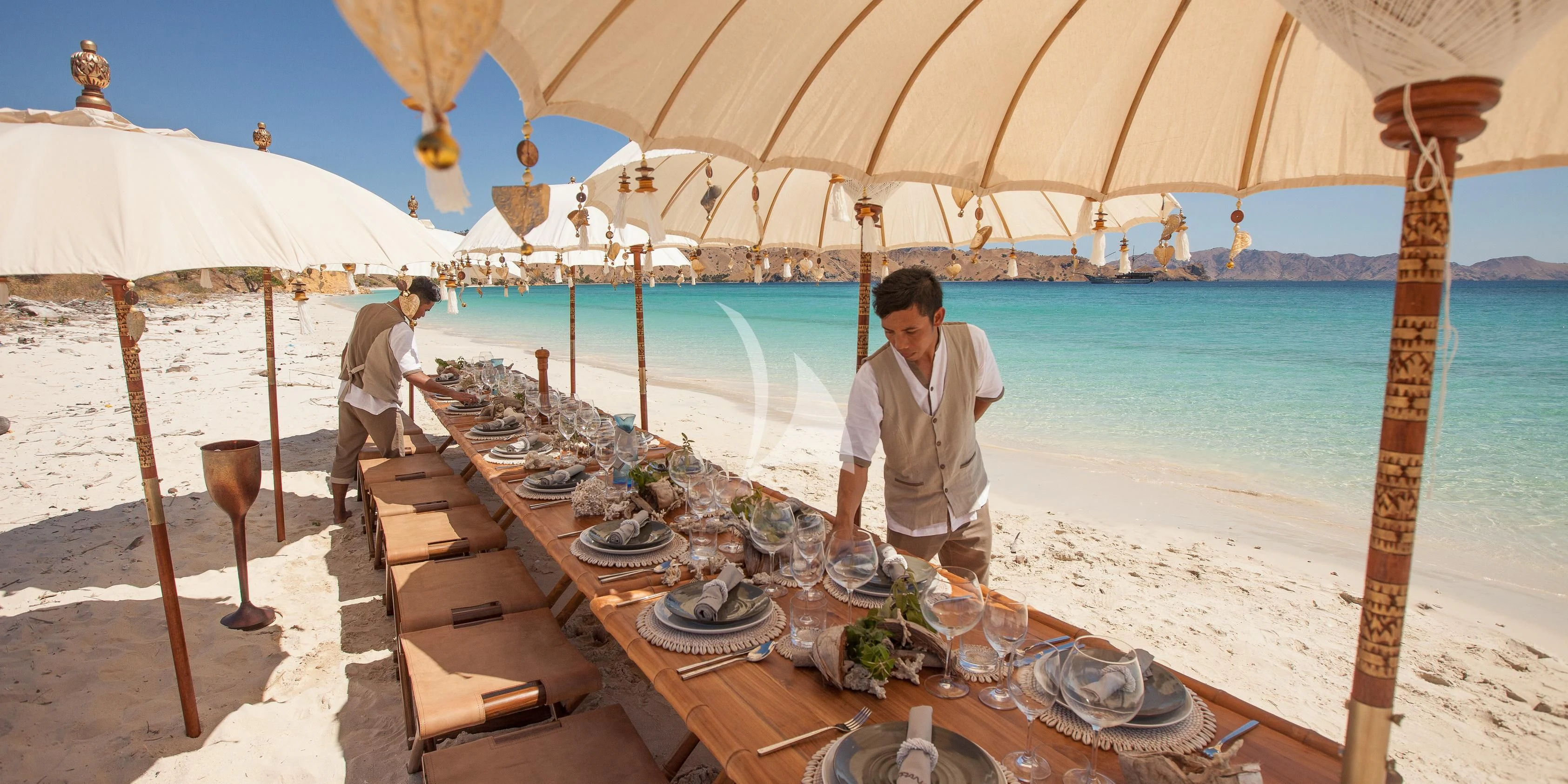 a person standing under an umbrella at a table with food on it aboard PRANA Yacht for Charter