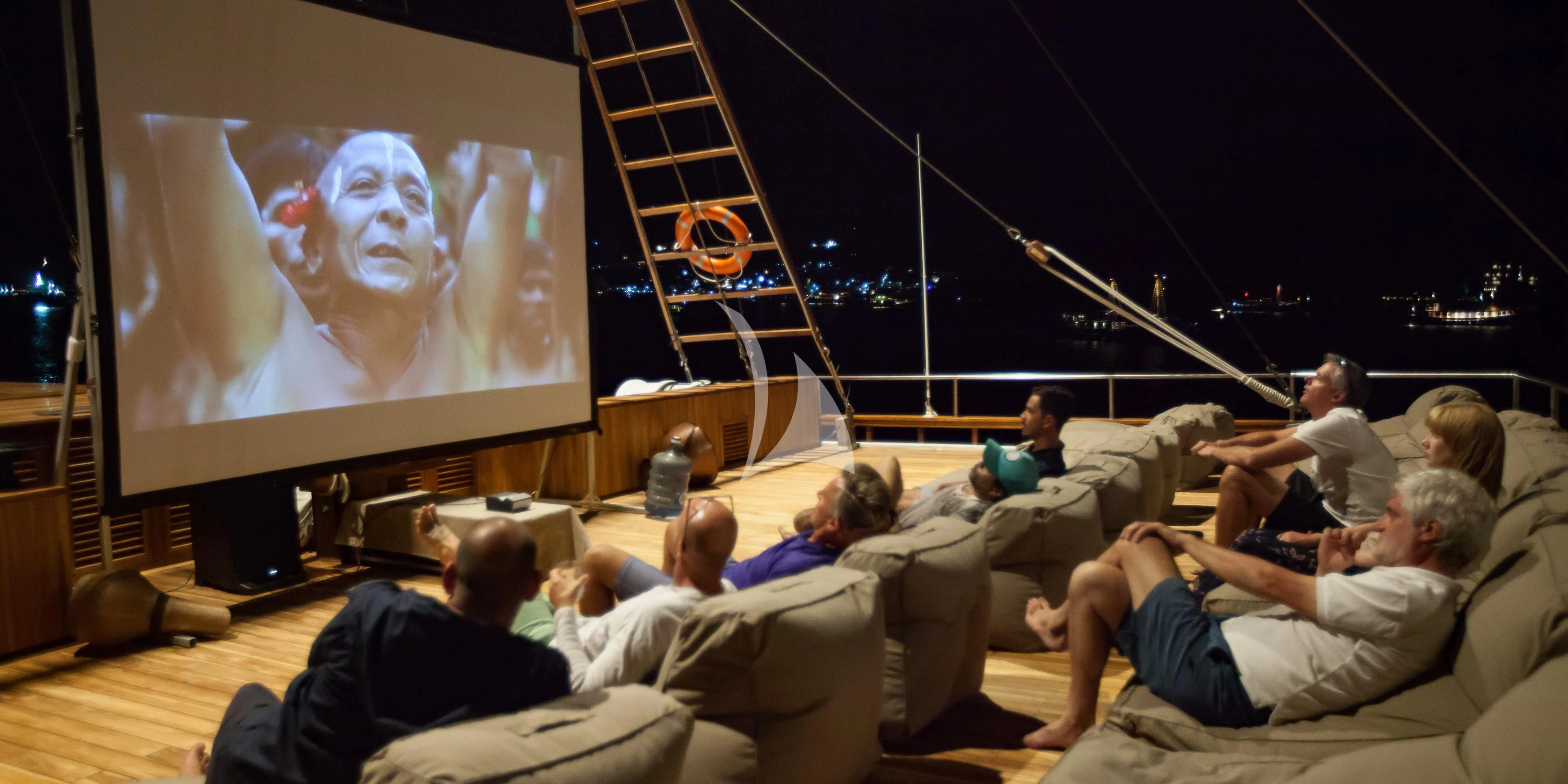 a group of people sitting on a couch watching a television aboard PRANA Yacht for Charter