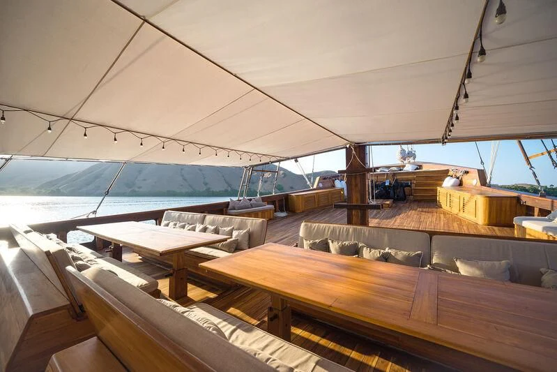 a room with wooden tables and a large window aboard PRANA Yacht for Charter