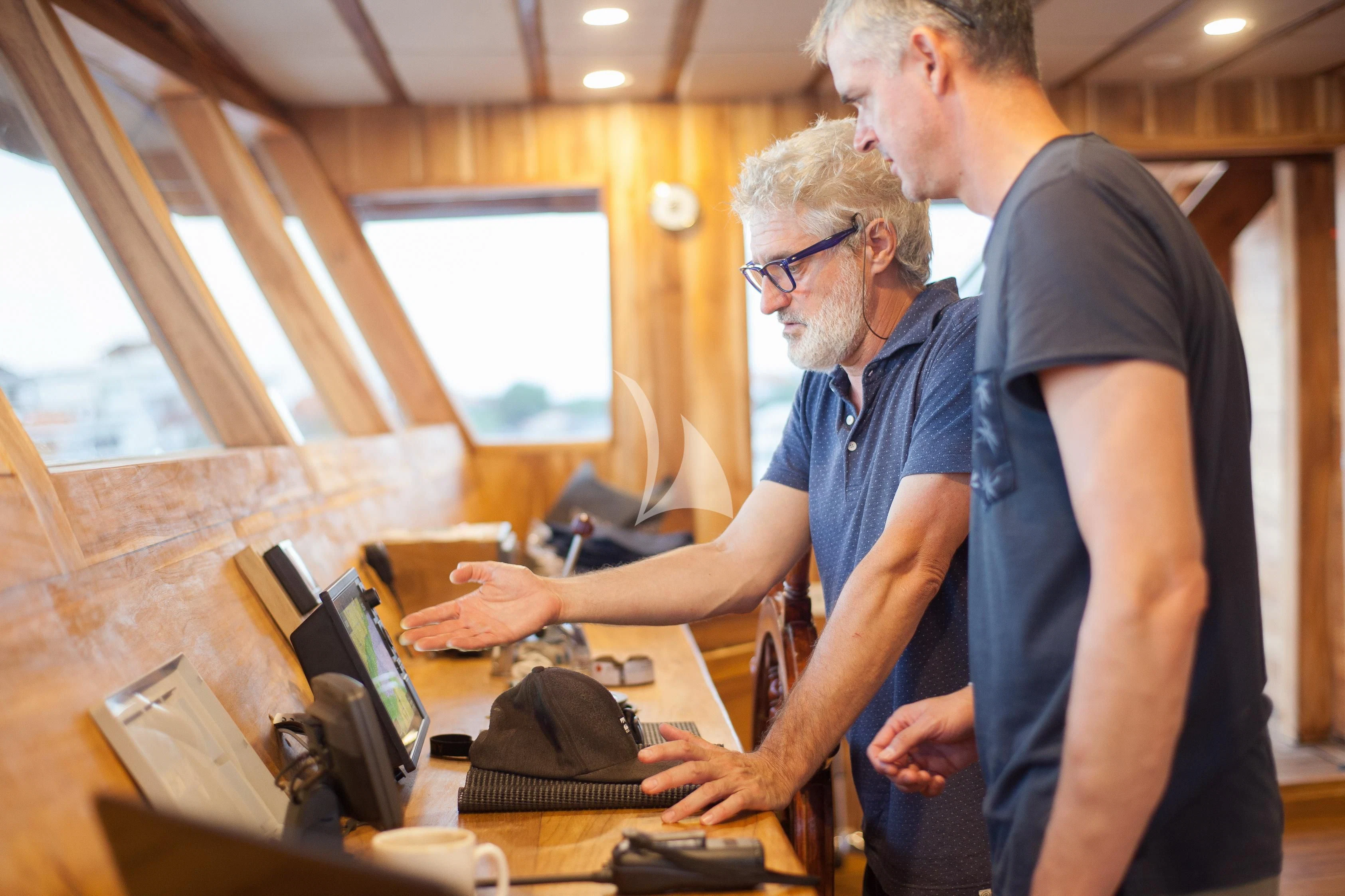a man and a woman looking at a laptop on a table aboard PRANA Yacht for Charter
