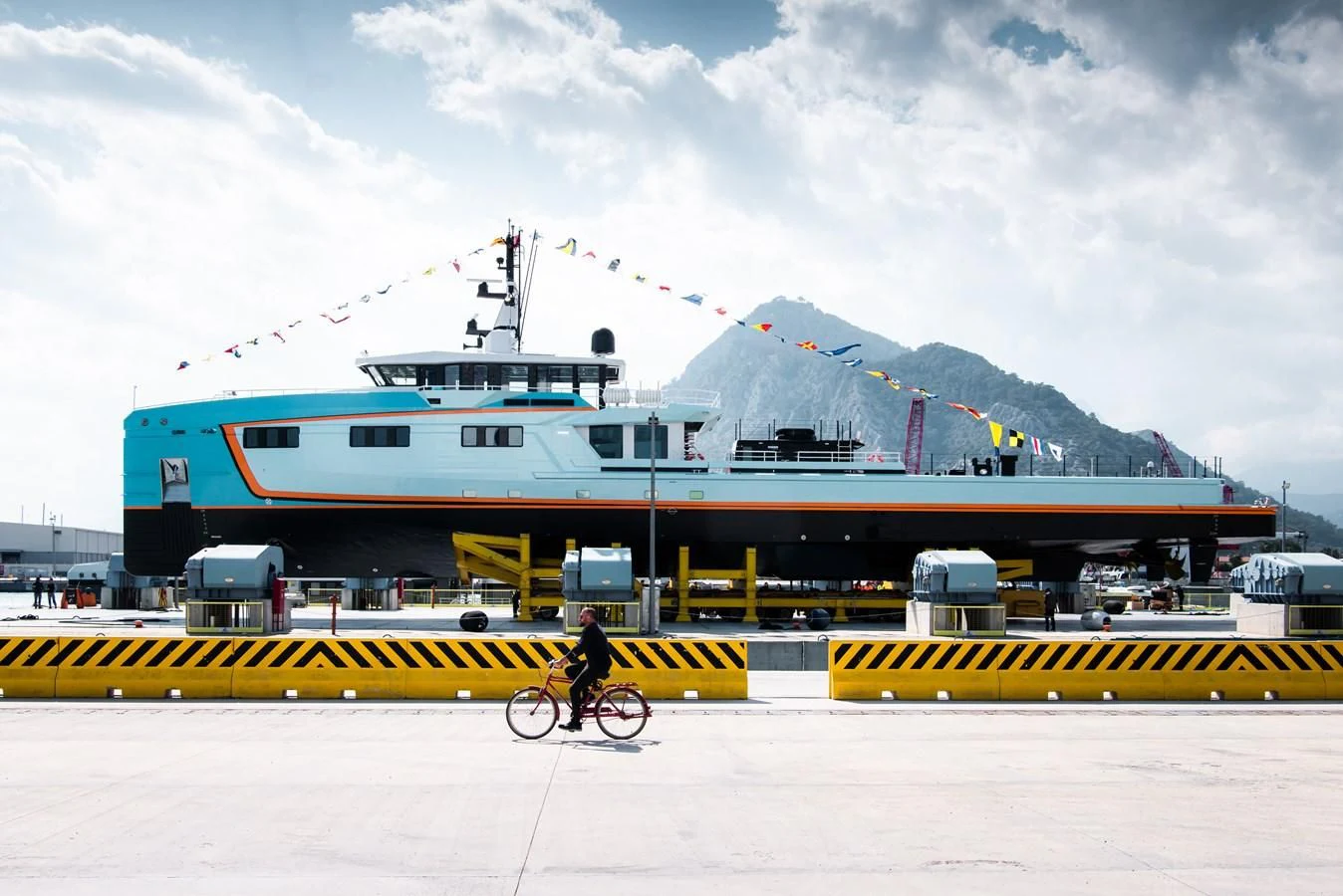 a person riding a bike in front of a large ship aboard FIVE OCEANS Yacht for Sale