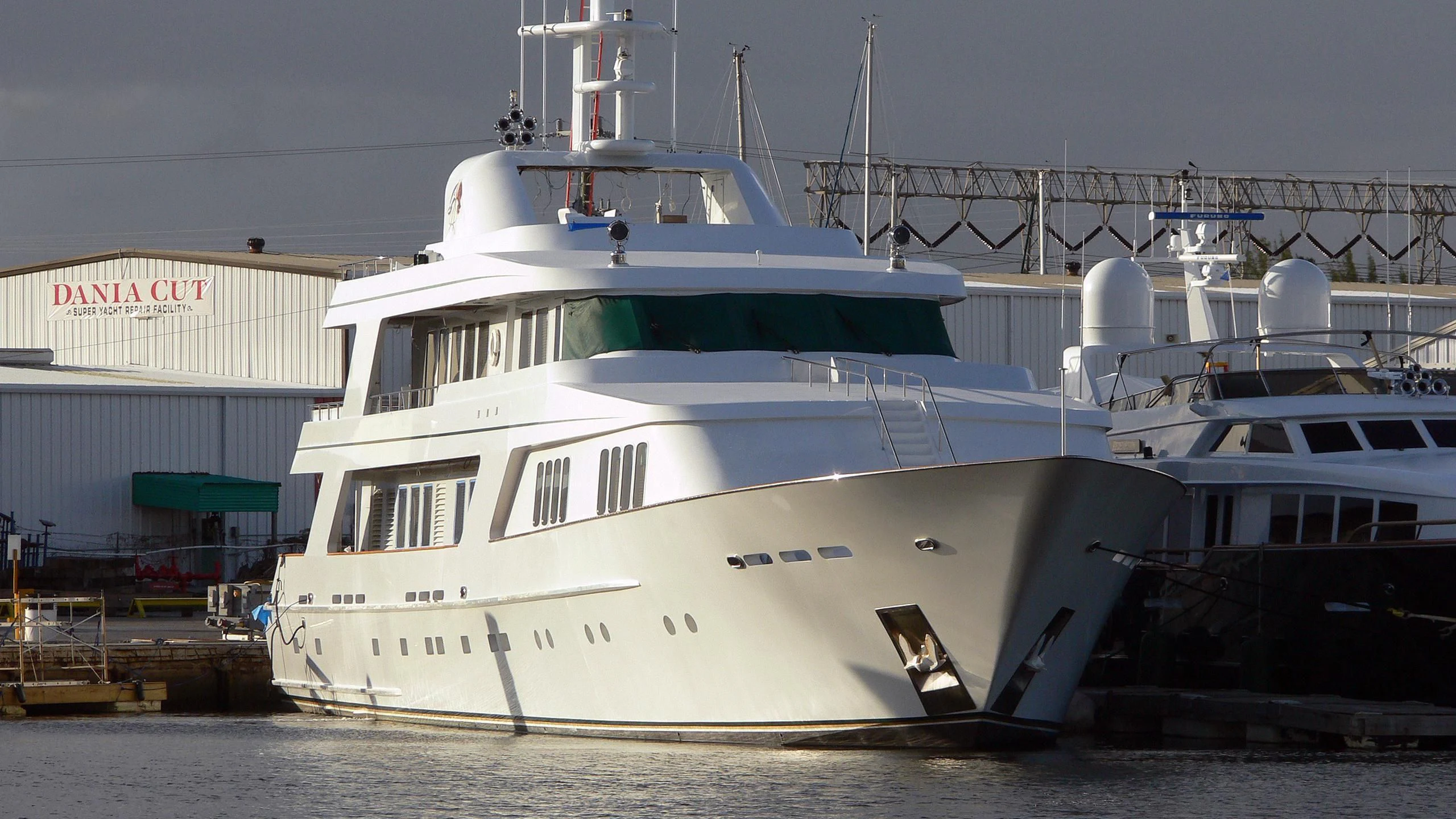 a large white boat sits in a harbor aboard DANADIA Yacht for Sale