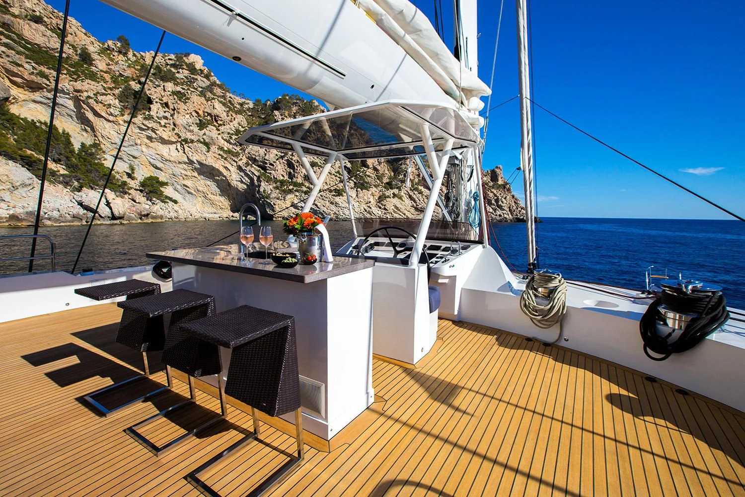 a deck with a table and chairs on it and a boat in the water aboard MASHUA BLUU Yacht for Sale