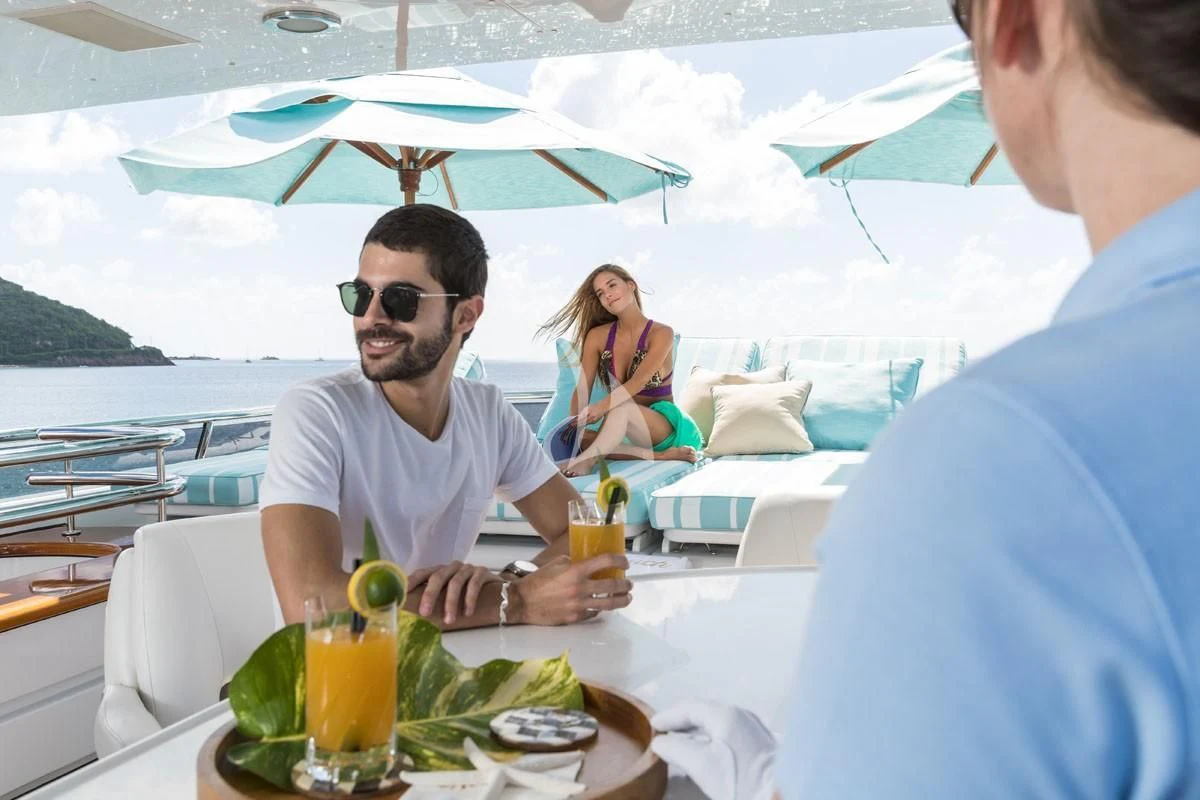 a man and woman sitting at a table with drinks and umbrellas aboard TOUCH Yacht for Sale