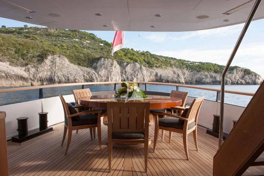 a table and chairs on a deck overlooking a body of water aboard ICE LADY Yacht for Sale
