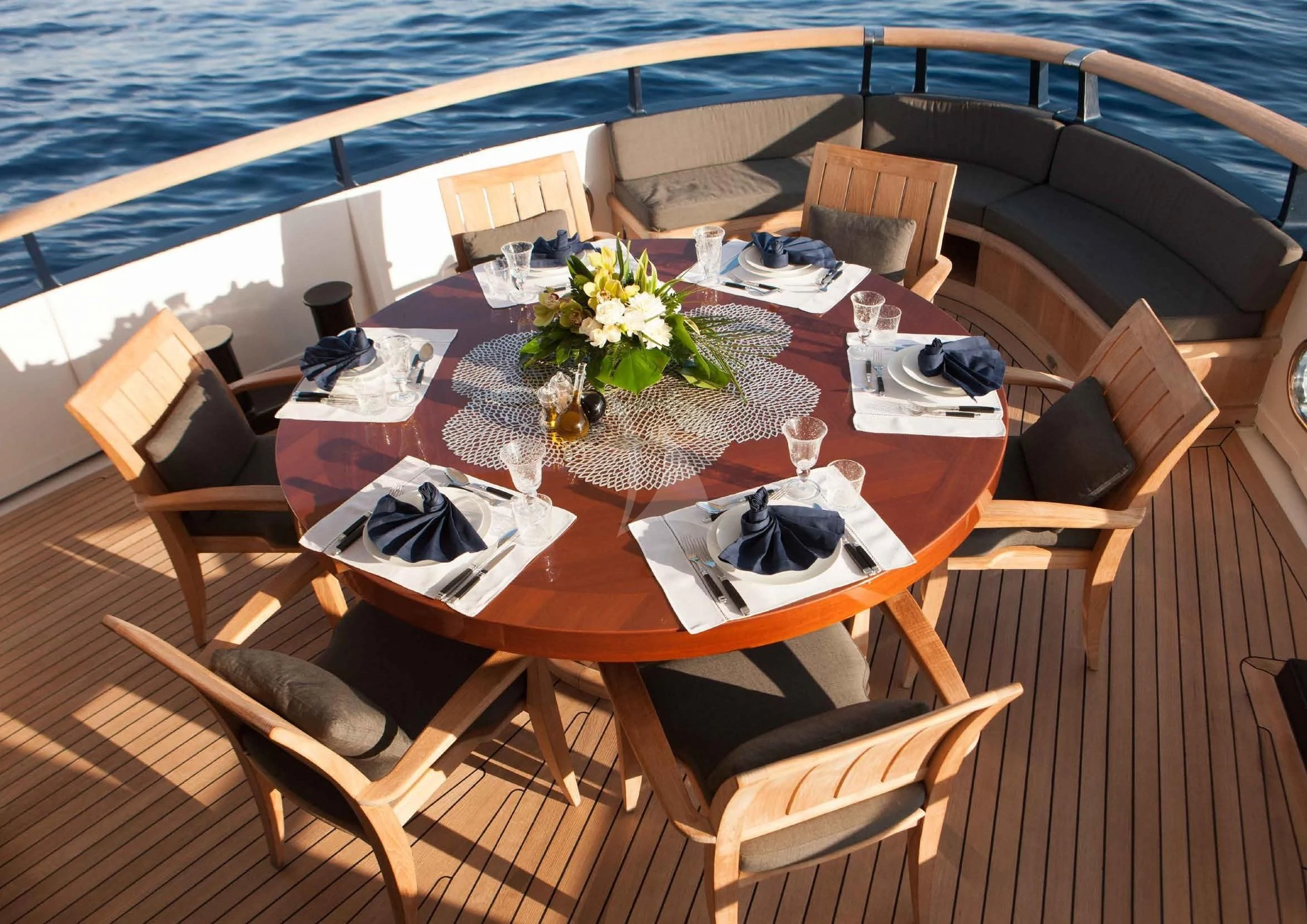 a table with chairs and a large body of water in the background aboard ICE LADY Yacht for Sale
