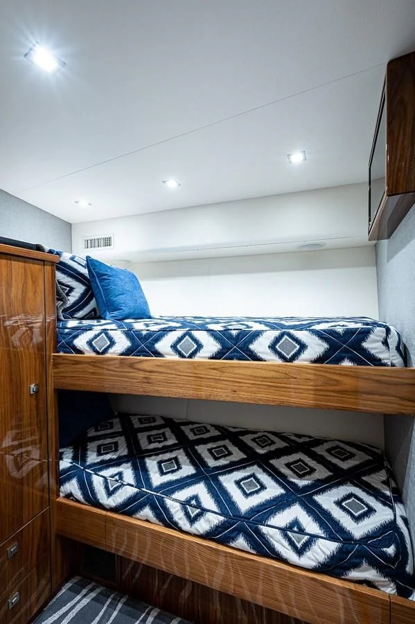 a bed with a blue and white comforter and a wooden headboard aboard SURFBUM Yacht for Sale