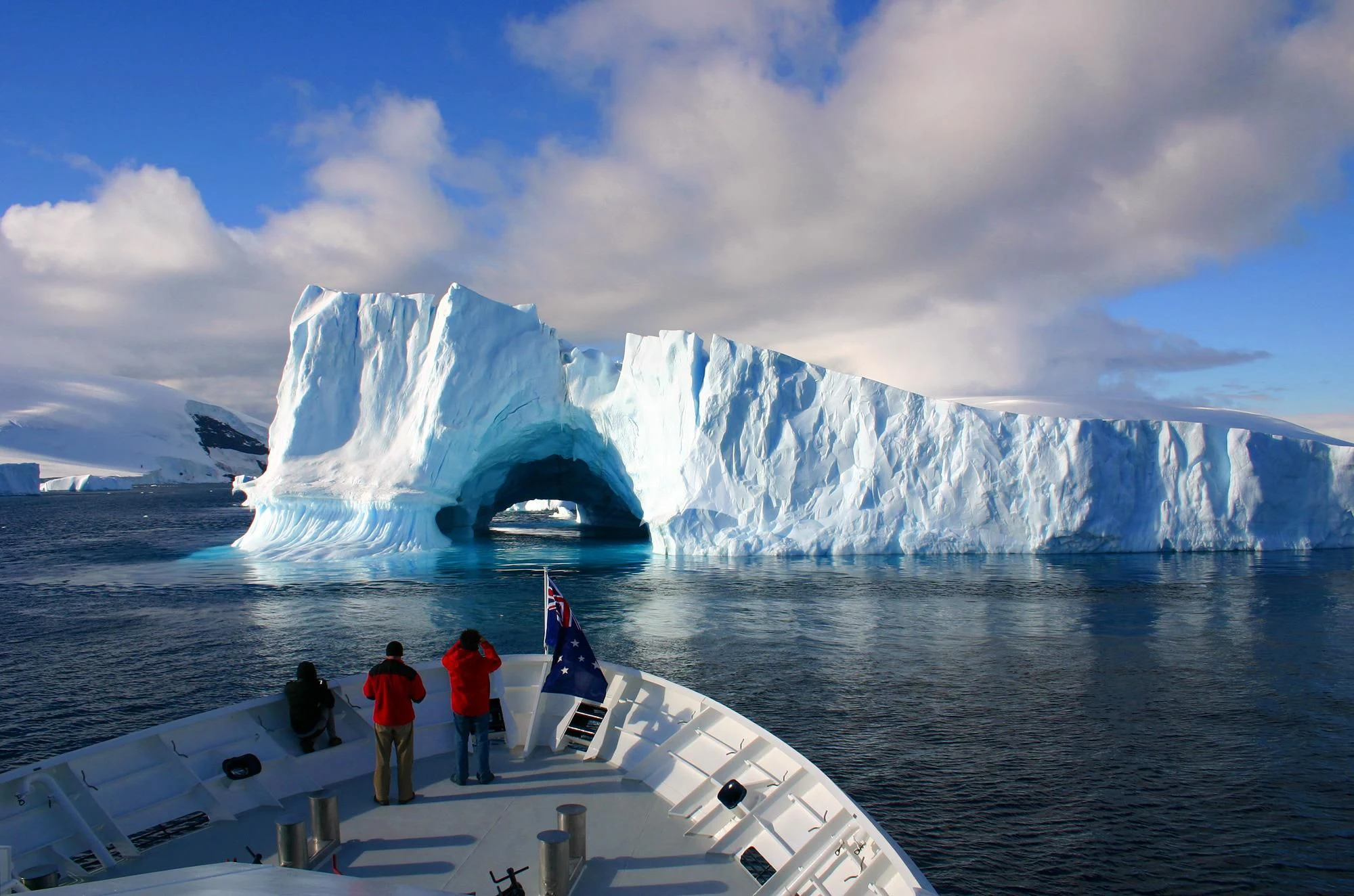 a group of people on a boat in the water with icebergs in the background aboard HANSE EXPLORER Yacht for Sale