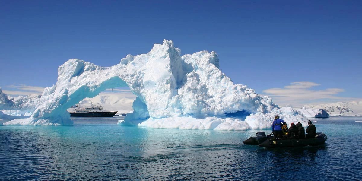 a group of people on a boat in the water with icebergs in the background aboard HANSE EXPLORER Yacht for Sale