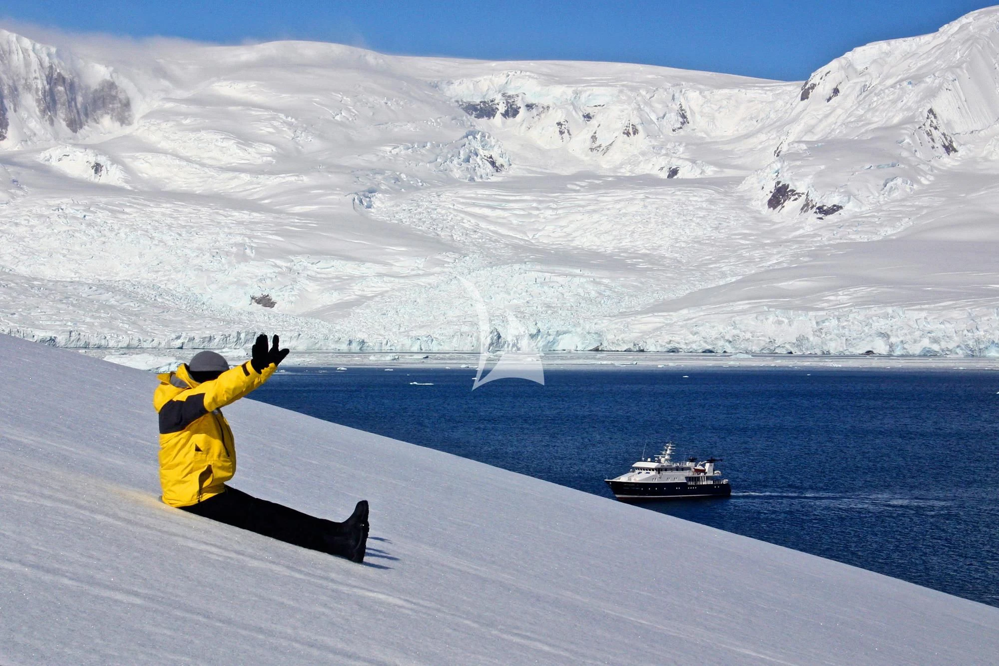 a person sitting on a snowy hill with a boat in the water aboard HANSE EXPLORER Yacht for Sale