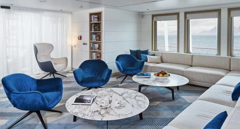 a living room with blue chairs and a white couch aboard HANSE EXPLORER Yacht for Sale