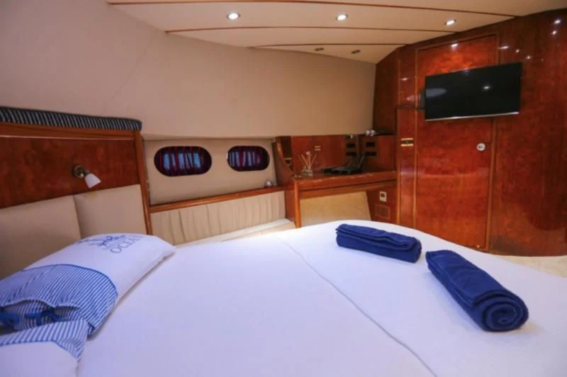 a bed with a white sheet and a black device on the wall aboard ERDOGAN Yacht for Sale