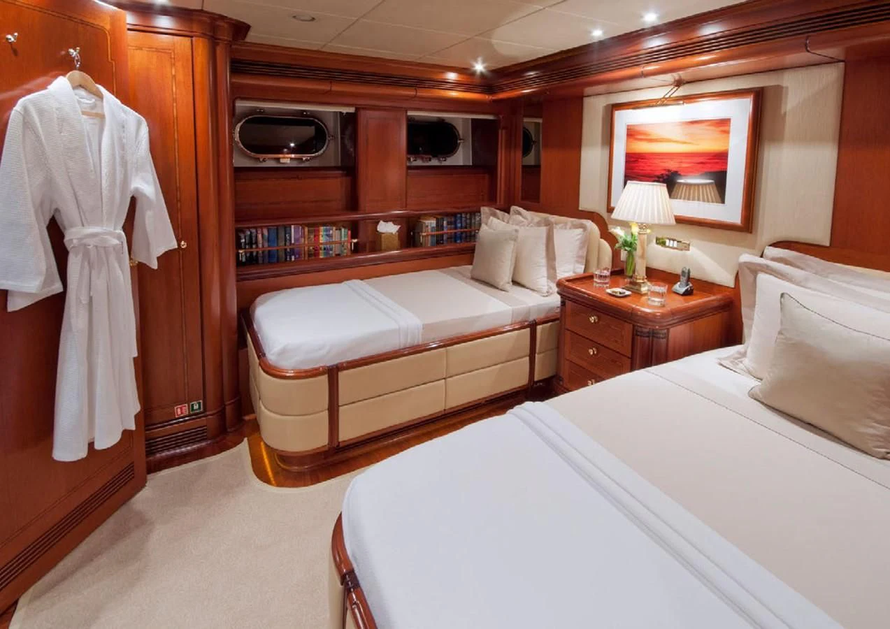 a room with a bed and a dresser aboard HYPERION Yacht for Charter