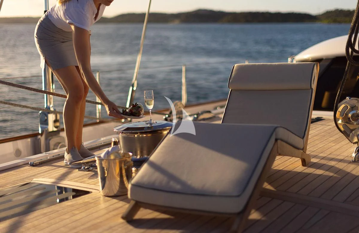 a woman pouring a drink into a glass on a boat aboard HYPERION Yacht for Charter