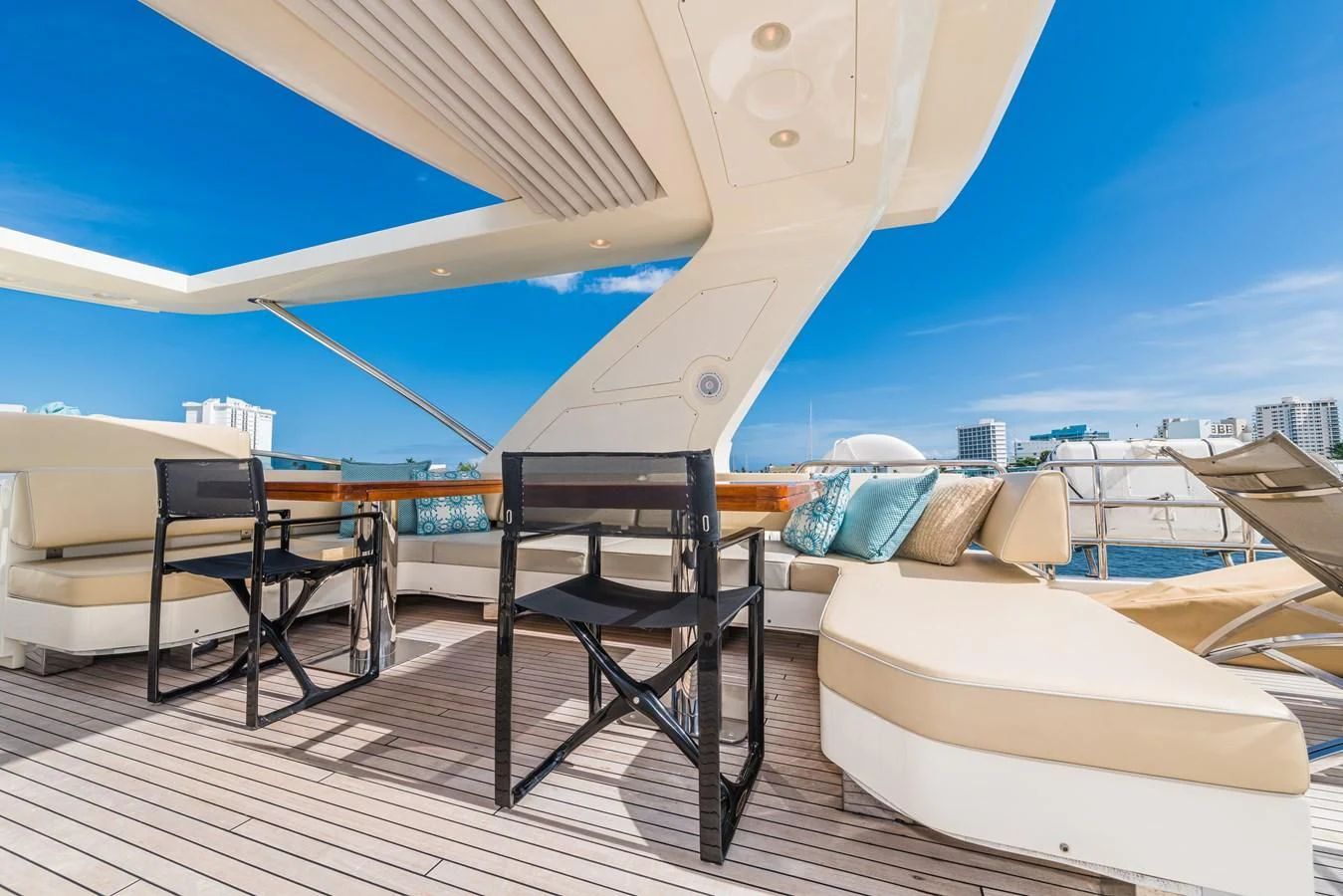 a lounge chair and a bed on a deck with a view of the city aboard LIBERTY BLUE Yacht for Sale