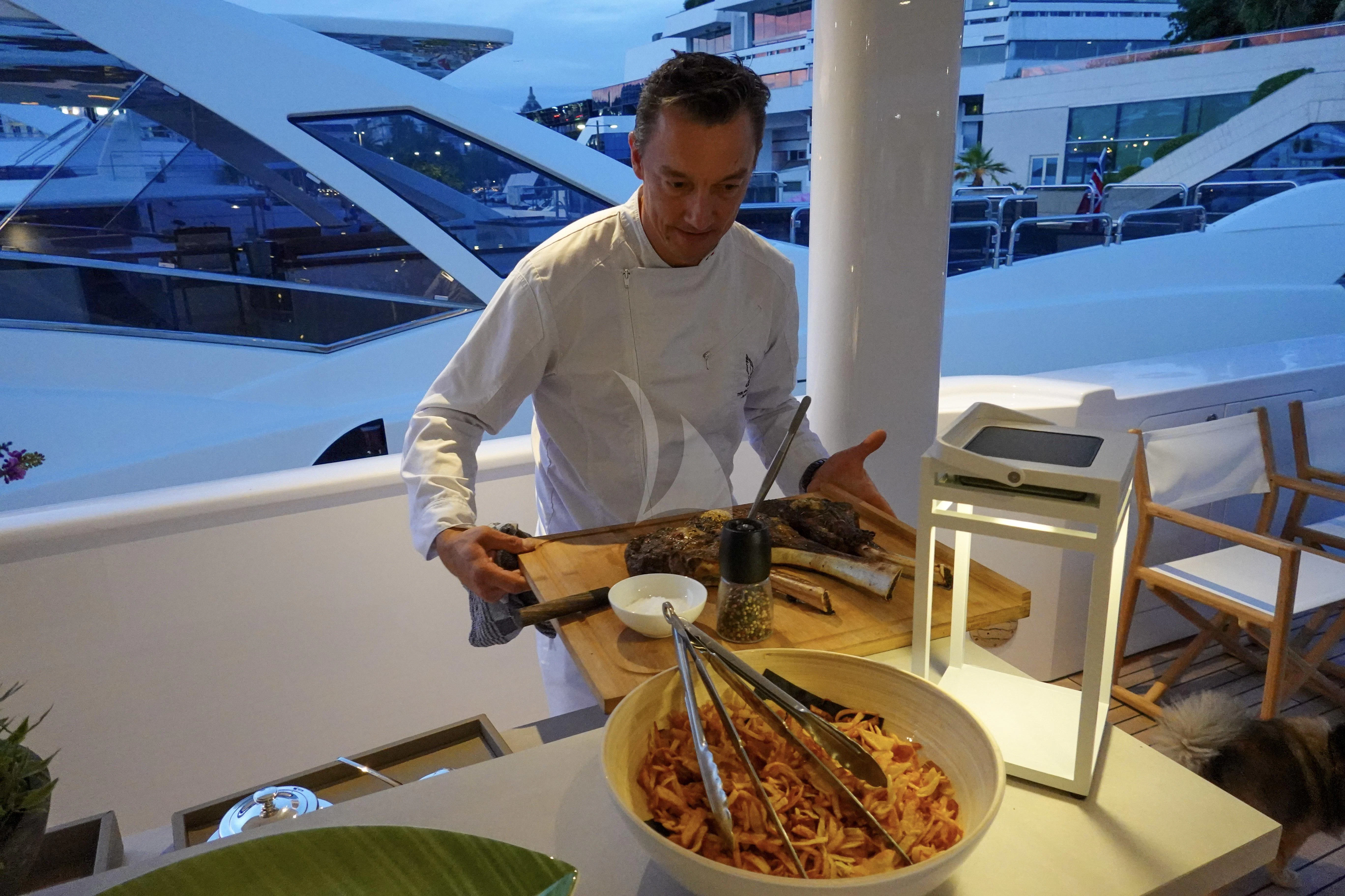 a man cooking food on a table aboard UNEXPECTED Yacht for Sale