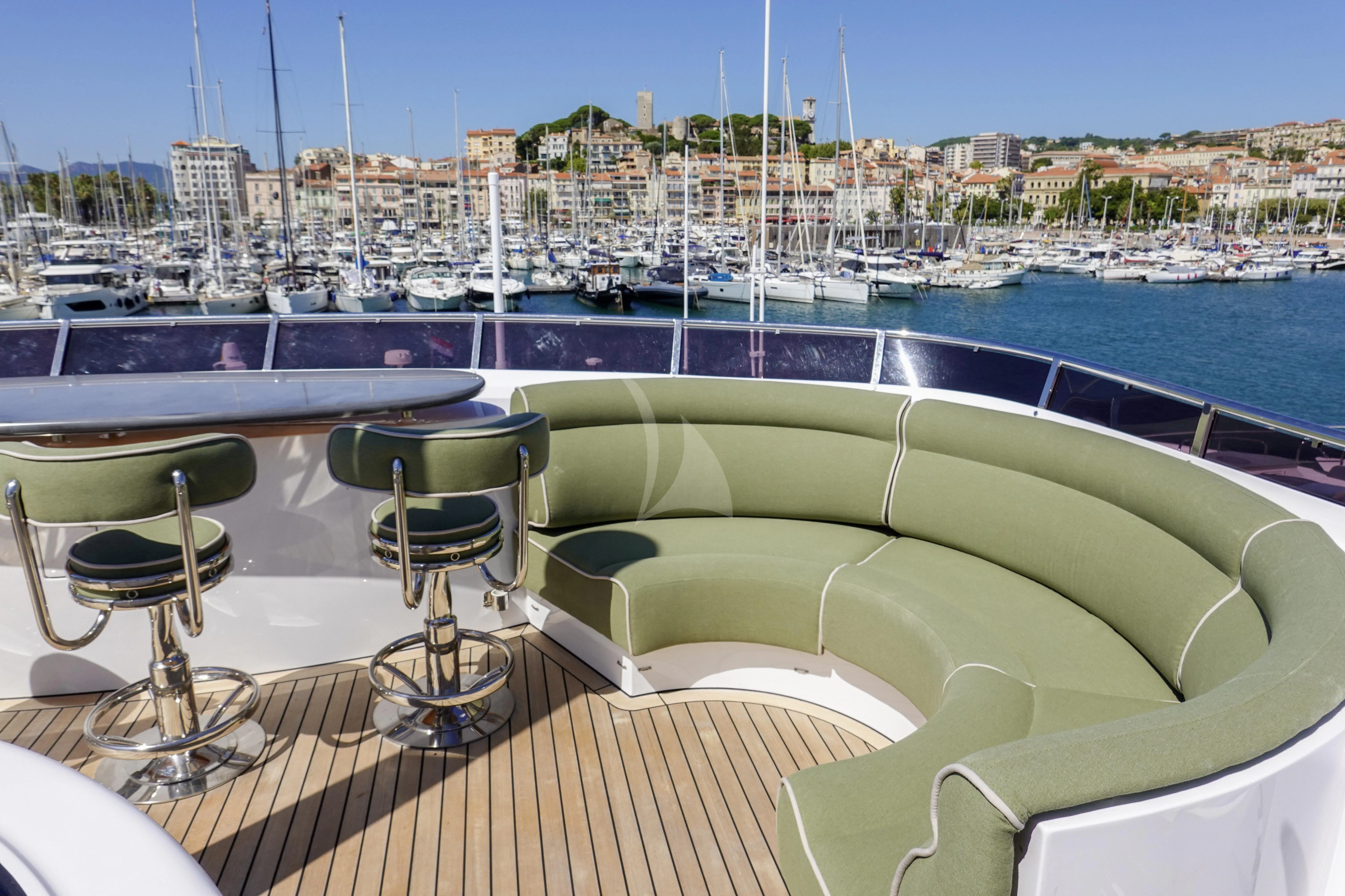 a deck with chairs and tables on it by a body of water aboard UNEXPECTED Yacht for Sale