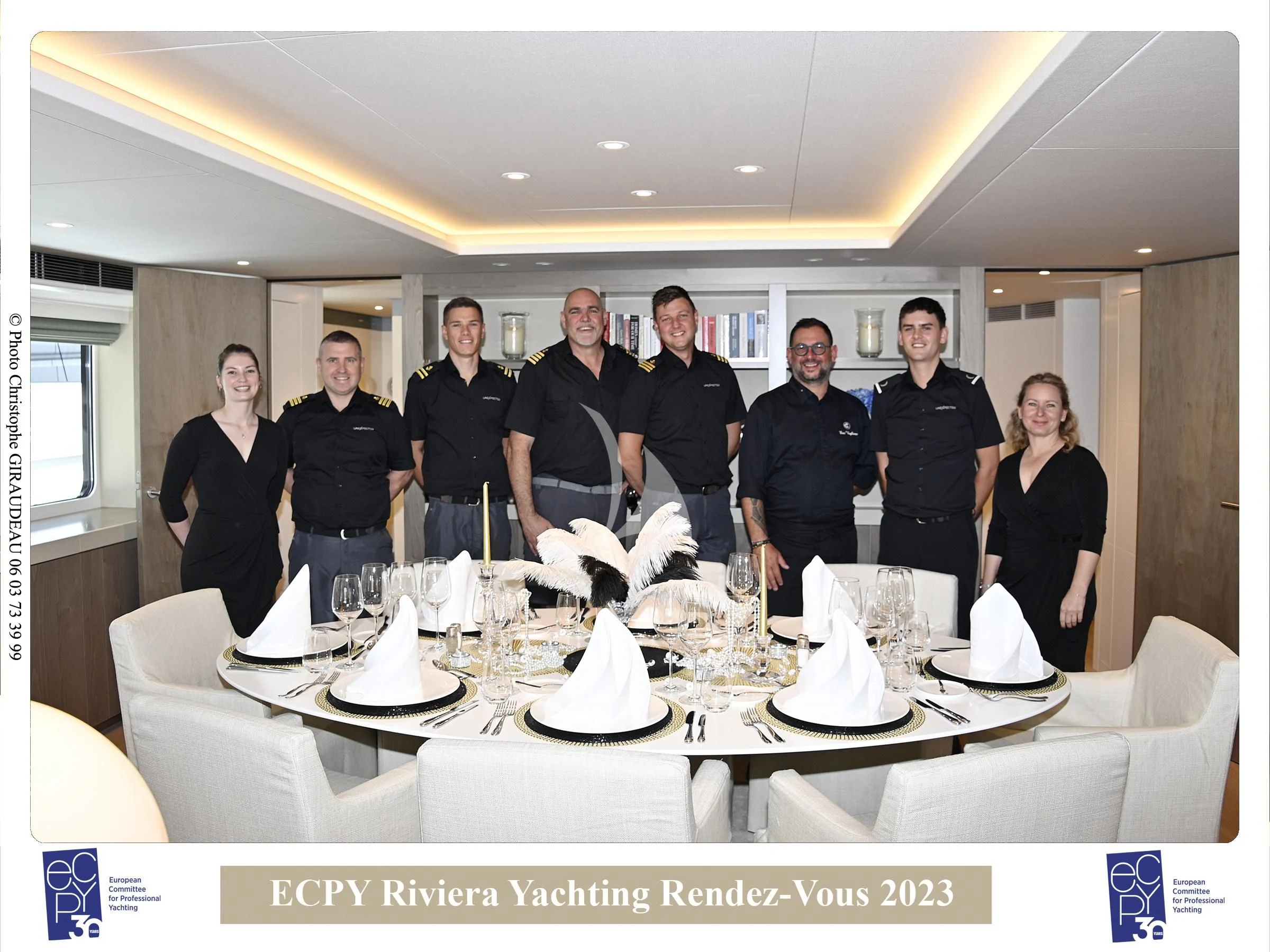a group of people standing around a table with plates and cups aboard UNEXPECTED Yacht for Sale