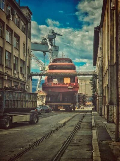 a train track with buildings and a crane in the background aboard BIRUBI Yacht for Sale