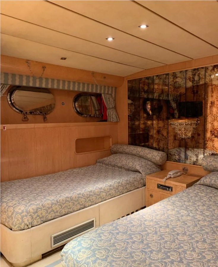 a bedroom with a bed and a fireplace aboard BAHIRA II Yacht for Sale