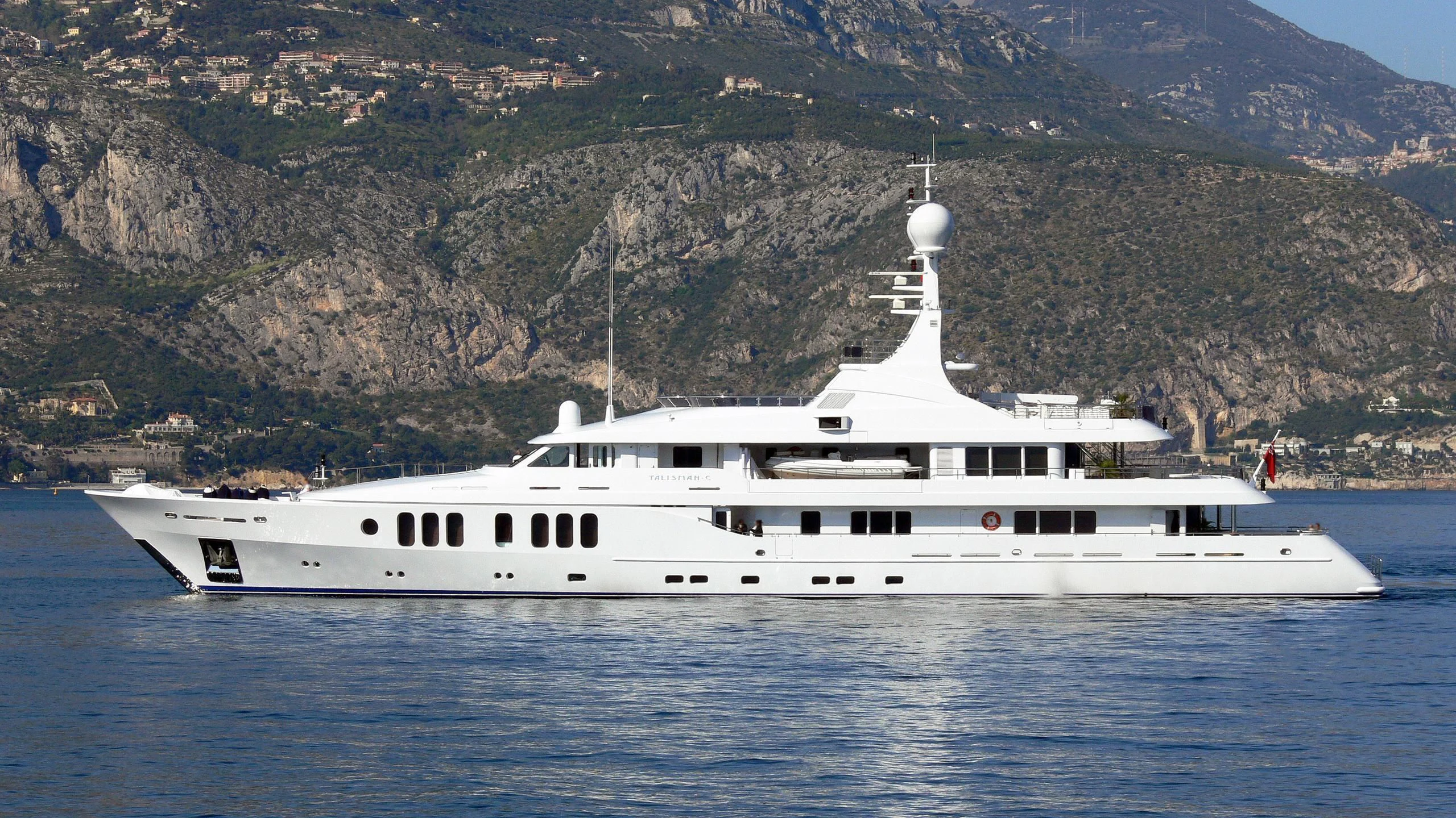 a white yacht in front of a mountain aboard TALISMAN MAITON Yacht for Charter