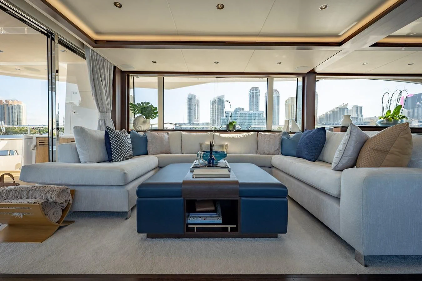 a living room with a blue couch and a large window aboard ROMANI Yacht for Sale