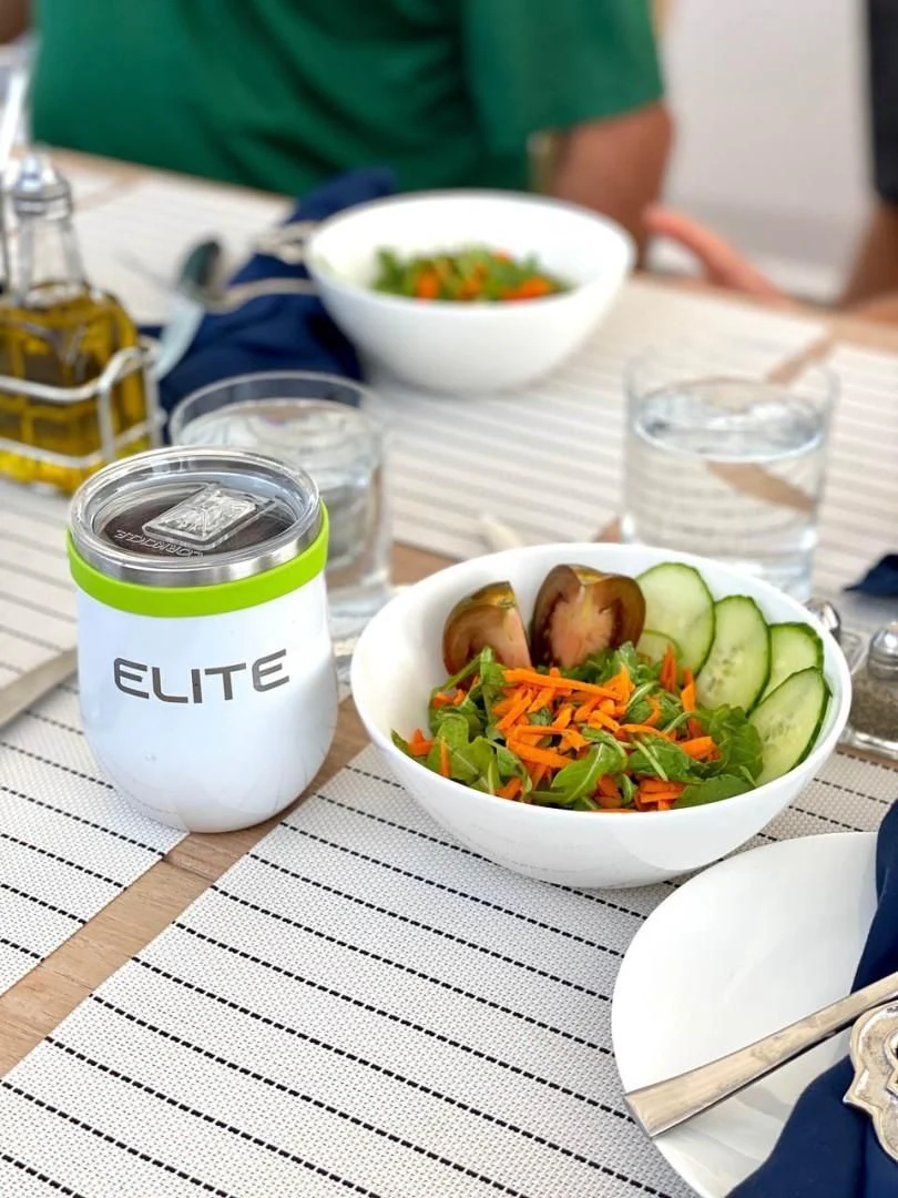 a bowl of salad and a can of water on a table aboard ELITE Yacht for Sale