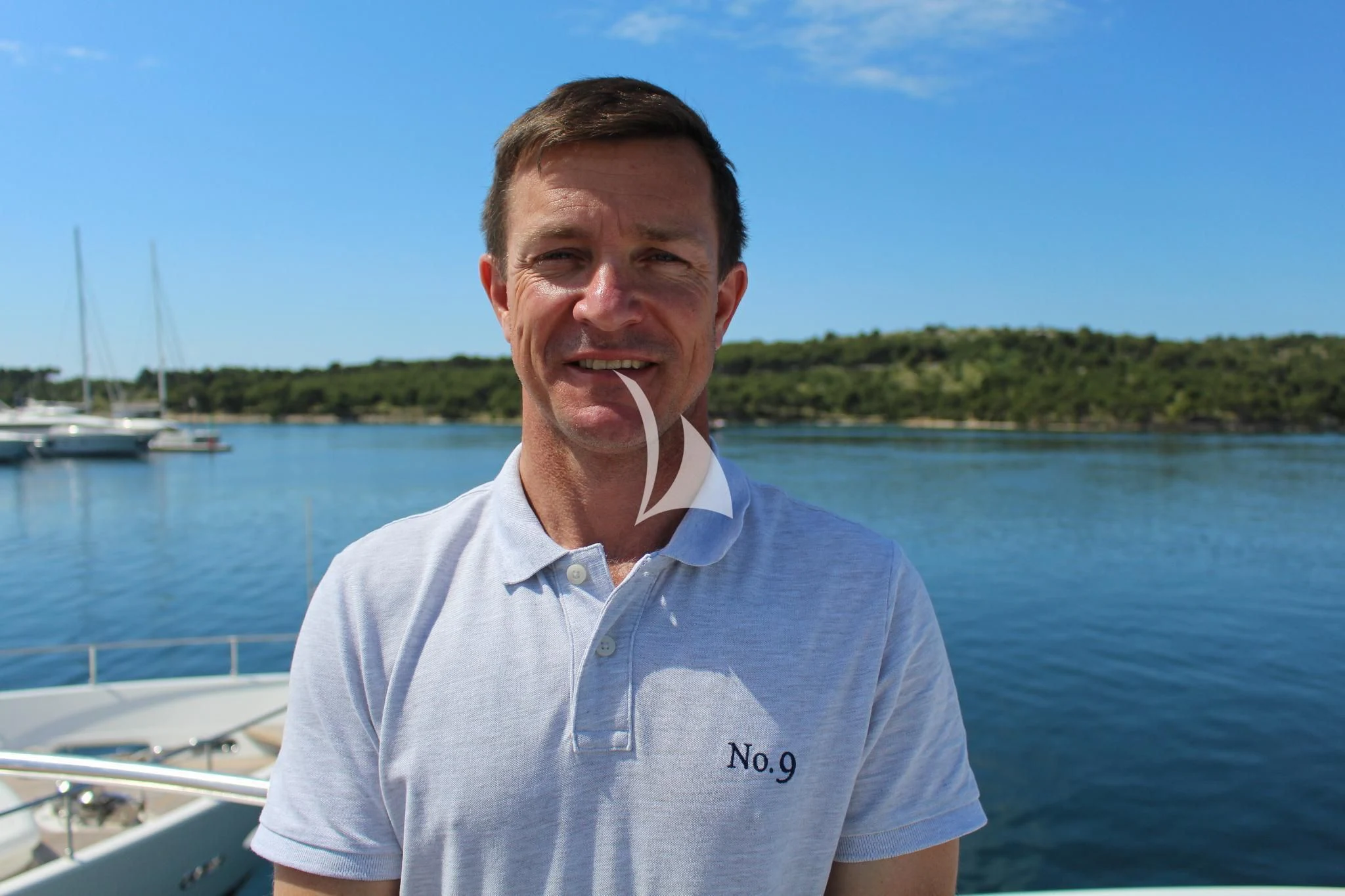 Nathan Fillion standing in front of a body of water with boats in the background aboard NO.9 Yacht for Sale