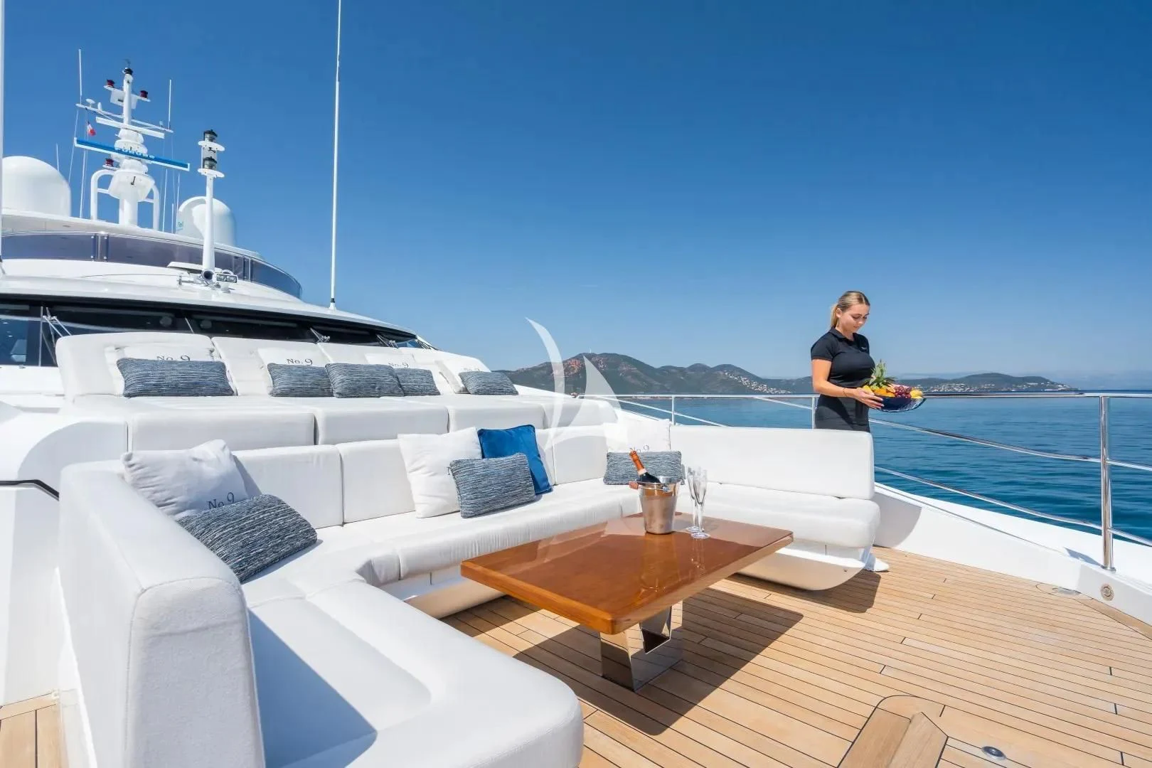 a person sitting on a couch on a deck with a large ship in the background aboard NO.9 Yacht for Sale