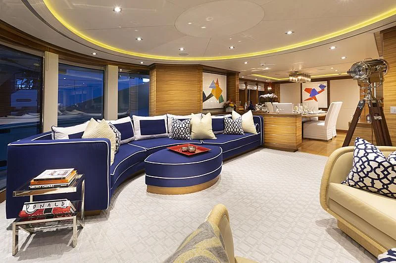 a large living room with a blue couch and a large mirror aboard LUMIR Yacht for Sale