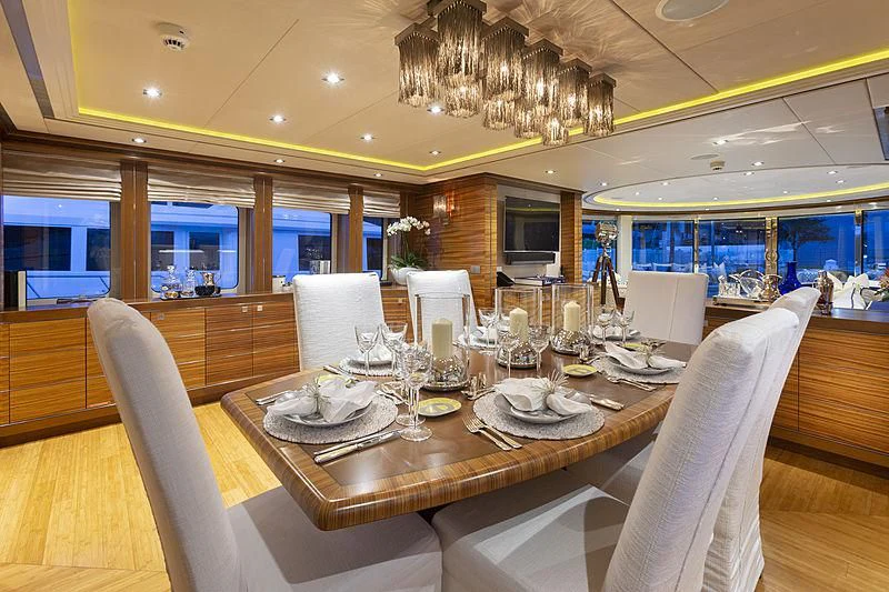 a large dining table with white chairs aboard LUMIR Yacht for Sale