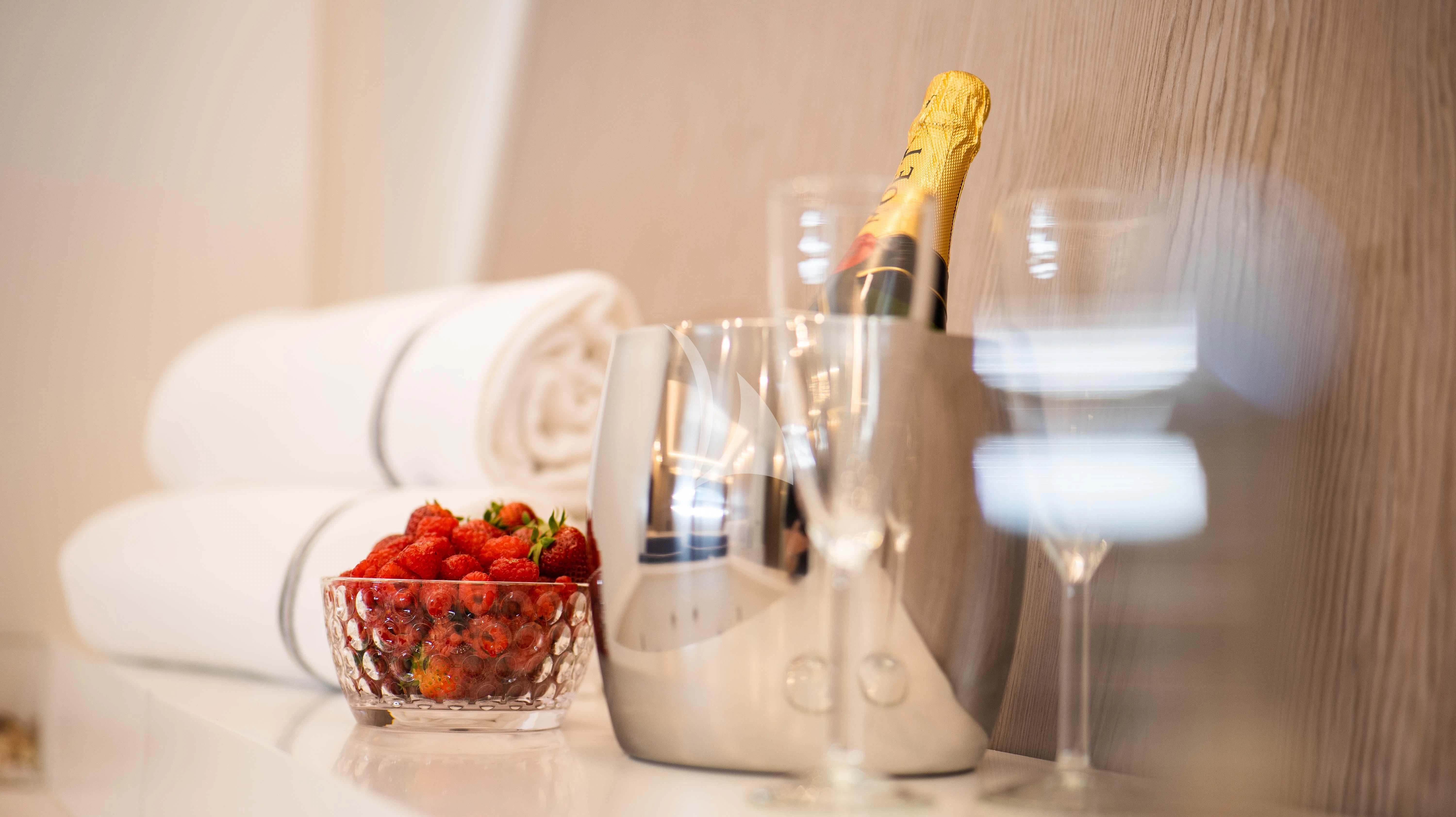 a bottle of champagne next to a bowl of fruit and glasses aboard BLUE DEVIL Yacht for Sale