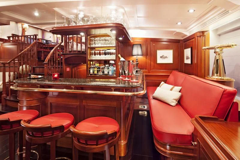a room with a bar and chairs aboard KAMAXITHA Yacht for Sale
