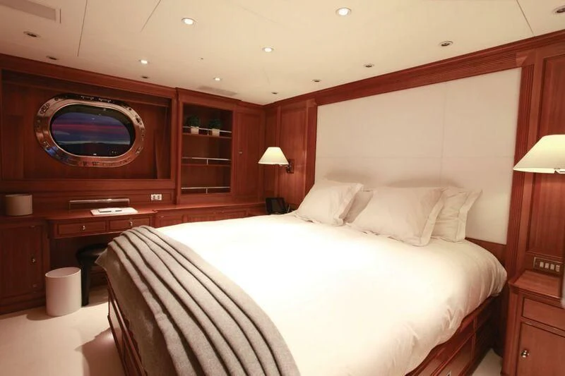 a bed with a white sheet and a television on the wall aboard PERSEUS Yacht for Sale