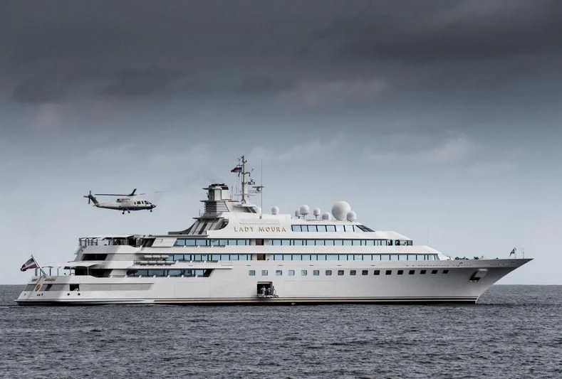 a large white ship with a helicopter flying over it aboard LADY MOURA Yacht for Sale