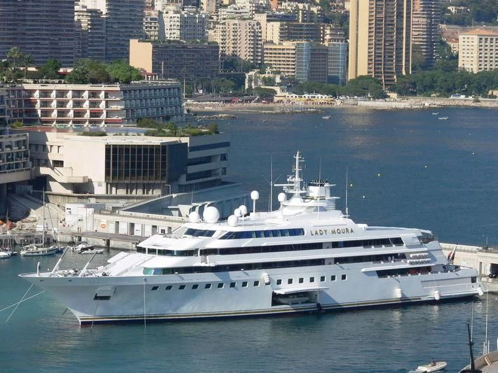 a large white boat in a harbor aboard LADY MOURA Yacht for Sale