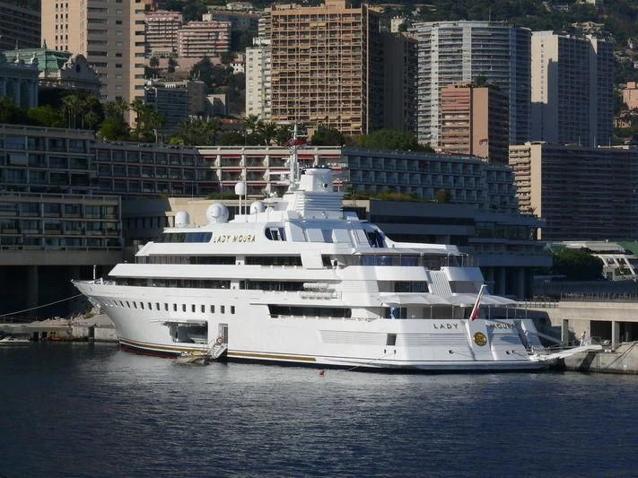 a large white boat in a harbor aboard LADY MOURA Yacht for Sale