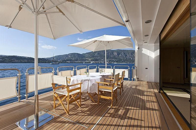 a deck with tables and chairs on it aboard LADY MOURA Yacht for Sale