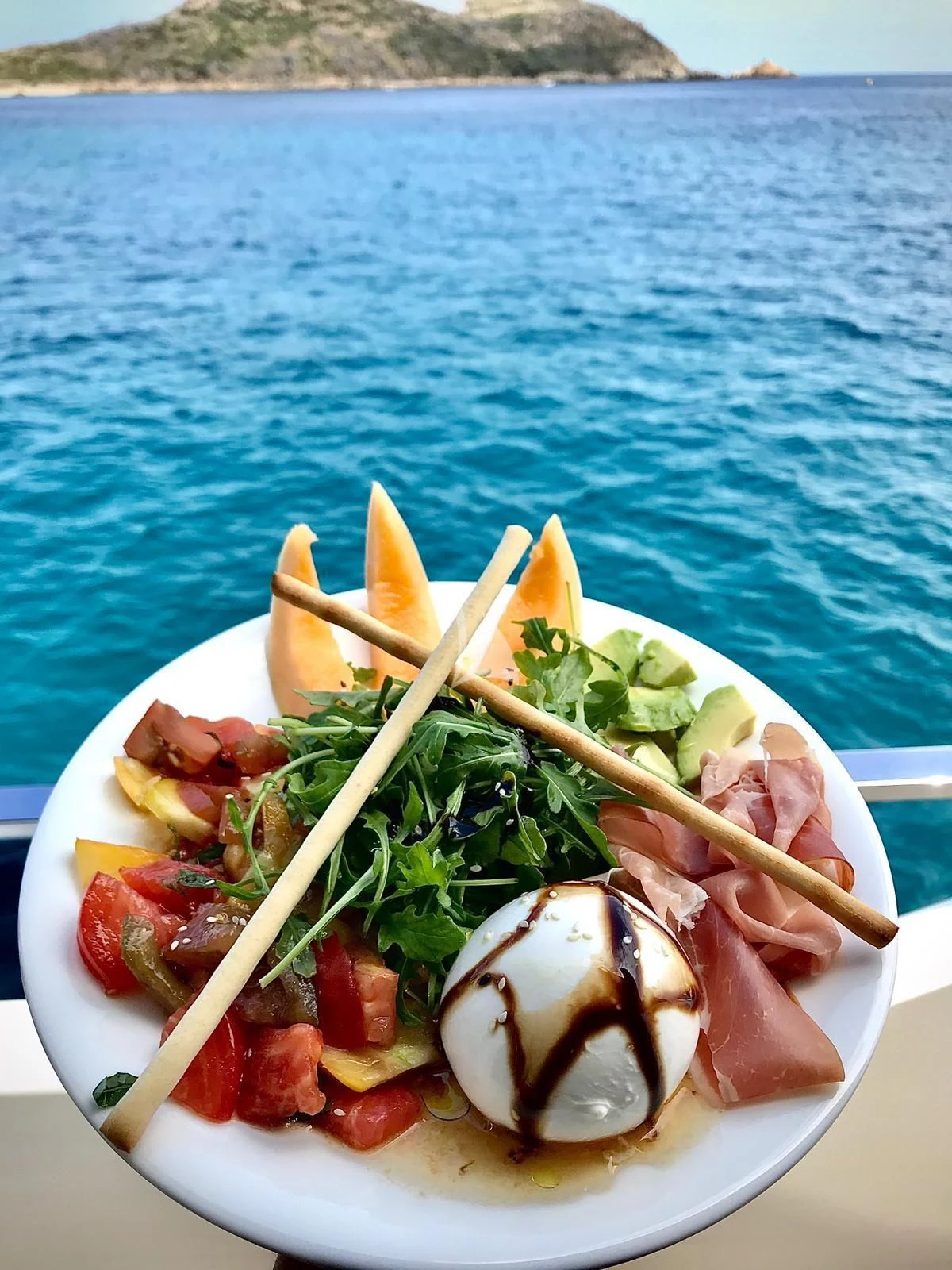 a plate of food on a beach aboard EPIC Yacht for Sale