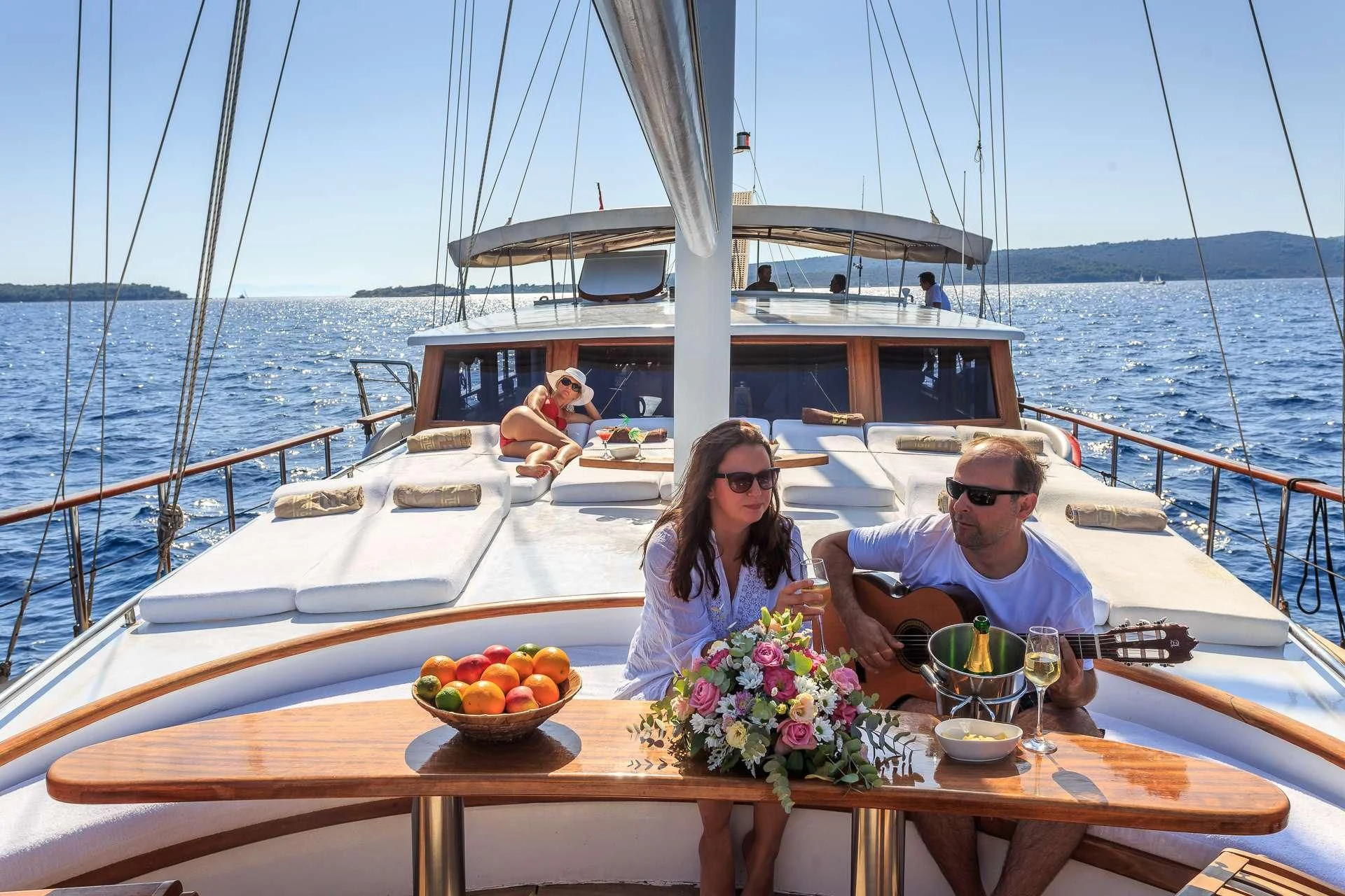 a man and woman sitting on a boat with a woman sitting in the water and a man sitting aboard ALLURE E Yacht for Sale