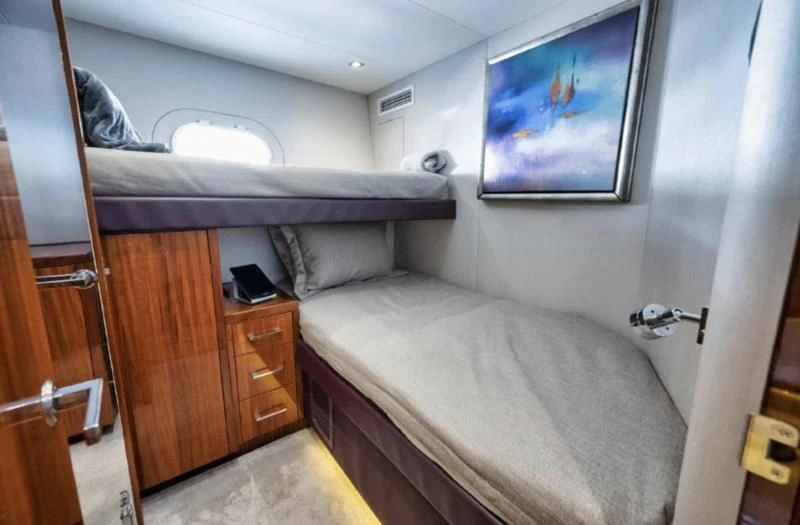 a bed with a desk and a television in a room aboard RITZ SEA Yacht for Sale