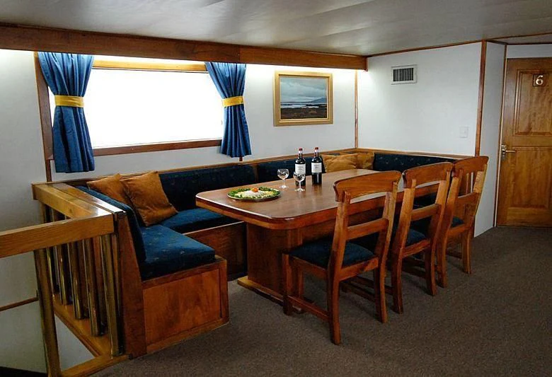 a living room with a table and couches aboard BELUGA Yacht for Sale
