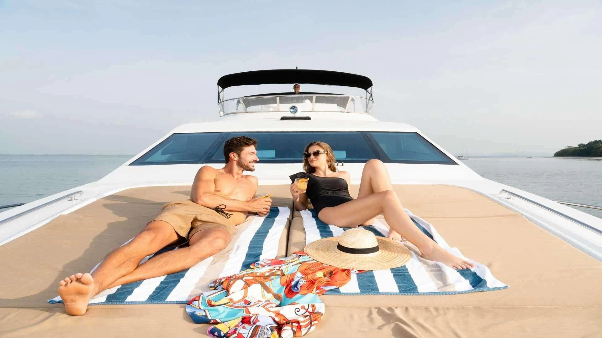 a man and woman sitting on a beach with a car aboard MIA KAI Yacht for Charter
