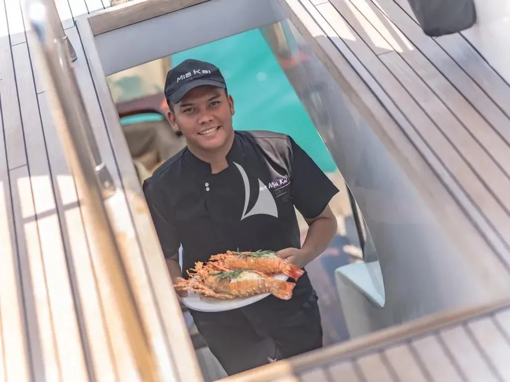 a man holding a pizza aboard MIA KAI Yacht for Charter